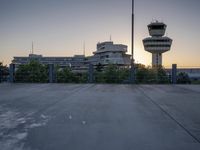 some cars are parked at an air traffic control tower with smoke coming from the air