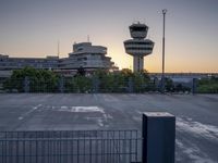 some cars are parked at an air traffic control tower with smoke coming from the air