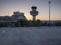 some cars are parked at an air traffic control tower with smoke coming from the air