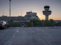 some cars are parked at an air traffic control tower with smoke coming from the air