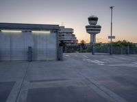some cars are parked at an air traffic control tower with smoke coming from the air
