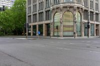 empty streets at an intersection with traffic lights and a building in the background that has an arched window