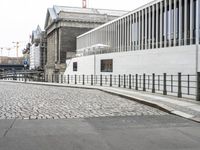 a building sitting in the middle of a road with a black fence at the top