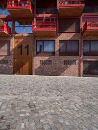 the outside of the building shows the two levels of balconies and windows, and has some flowers in the balcony plants