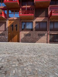 the outside of the building shows the two levels of balconies and windows, and has some flowers in the balcony plants