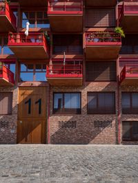 the outside of the building shows the two levels of balconies and windows, and has some flowers in the balcony plants