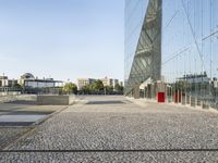 a long walkway is in front of the building's reflection and surrounding its very large windows