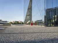 a long walkway is in front of the building's reflection and surrounding its very large windows