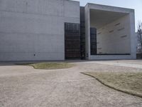 the large concrete structure has several windows and doors around it with small grass on top