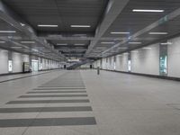 an empty walkway in a building with long black and white lines on the floor near stairs