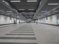 an empty walkway in a building with long black and white lines on the floor near stairs