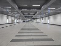 an empty walkway in a building with long black and white lines on the floor near stairs