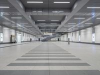 an empty walkway in a building with long black and white lines on the floor near stairs