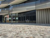 a sidewalk that has glass on the sides and an empty walkway underneath it with some buildings near it