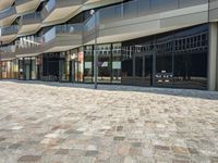 a sidewalk that has glass on the sides and an empty walkway underneath it with some buildings near it