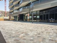 a sidewalk that has glass on the sides and an empty walkway underneath it with some buildings near it