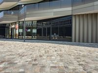 a sidewalk that has glass on the sides and an empty walkway underneath it with some buildings near it