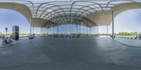 a very large modern building with huge glass roof over the street with bikes and people around it