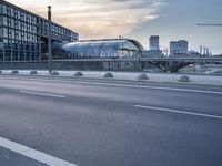 a road with an umbrella near a bridge and large buildings on both sides of the street