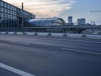 a road with an umbrella near a bridge and large buildings on both sides of the street