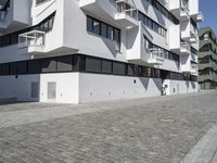 large blocky building with balconyed balconies and balconyes by large brick paved walkway