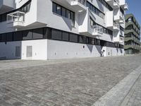 large blocky building with balconyed balconies and balconyes by large brick paved walkway