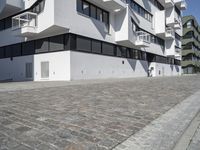 large blocky building with balconyed balconies and balconyes by large brick paved walkway