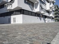 large blocky building with balconyed balconies and balconyes by large brick paved walkway