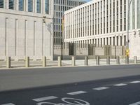 a man on a bike in an empty city street in front of a building and some pillars