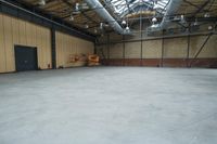 large empty room with steel wires and windows, exposed walls, and concrete flooring