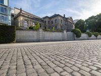 the stone wall is in front of a building with many windows and bushes on either side