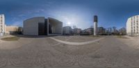 a spherical 360 - fish eye photo shows buildings and a statue in the background, with a clock tower in front