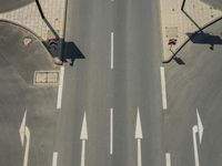 an aerial shot of an empty road, with a red traffic light on each side