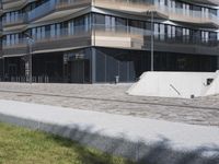a brick building with glass windows and sidewalk leading to it and a black fire hydrant