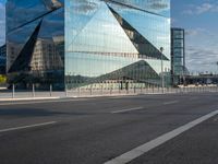 the tall glass building is reflected in the mirror's walls of the building by the street