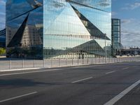 the tall glass building is reflected in the mirror's walls of the building by the street