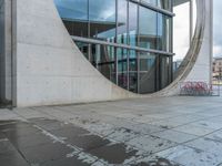 an outdoor area in the daytime with reflections on the windows and in the pavement it is snowing