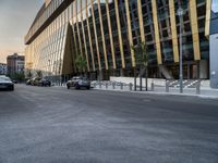 an empty road in front of some very tall buildings next to a busy street with cars and motorcycles