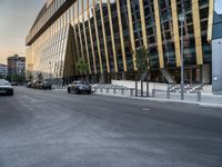 an empty road in front of some very tall buildings next to a busy street with cars and motorcycles