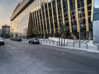 an empty road in front of some very tall buildings next to a busy street with cars and motorcycles