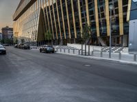 an empty road in front of some very tall buildings next to a busy street with cars and motorcycles