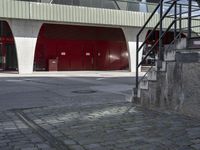 the steps lead from the ground to a building with red doors in front of it