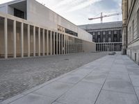 large empty walkway beside large buildings with large glass windows on sides of two walls in front of a building