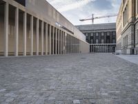 large empty walkway beside large buildings with large glass windows on sides of two walls in front of a building