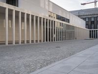 large empty walkway beside large buildings with large glass windows on sides of two walls in front of a building