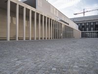 large empty walkway beside large buildings with large glass windows on sides of two walls in front of a building