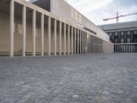 large empty walkway beside large buildings with large glass windows on sides of two walls in front of a building