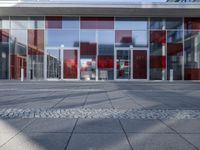 a large red building with multiple glass panels on the front doors and outside of them