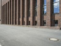 there are many windows that line a building and on the sidewalk, along with other red brick buildings