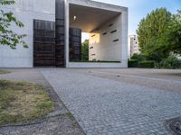 a building with concrete and glass, an entrance in the background and a bench with a wooden seat sitting in front